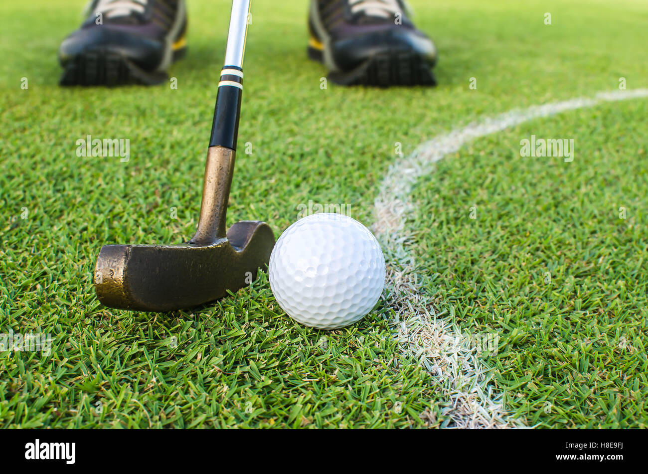 Golf player at the putting green hitting ball into a hole Stock Photo