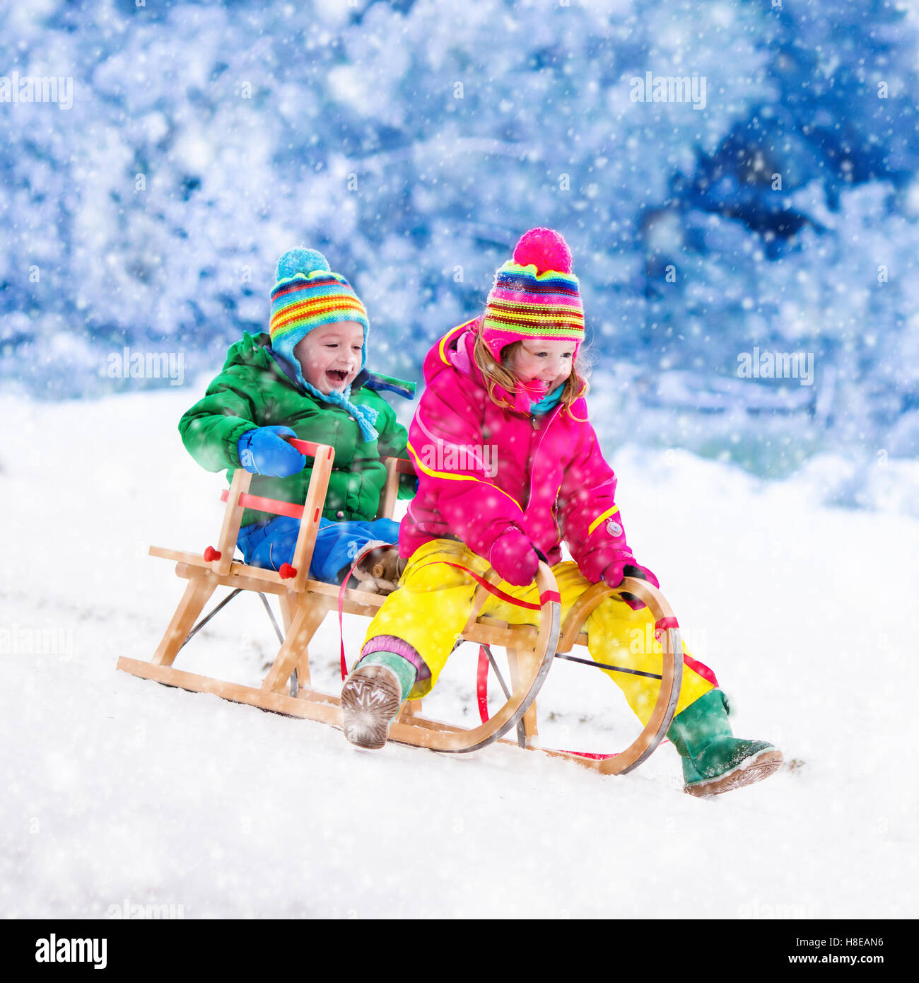 Infant Sleigh Riding Little girl and boy enjoy a sleigh ride. Child sledding. Toddler kid ...