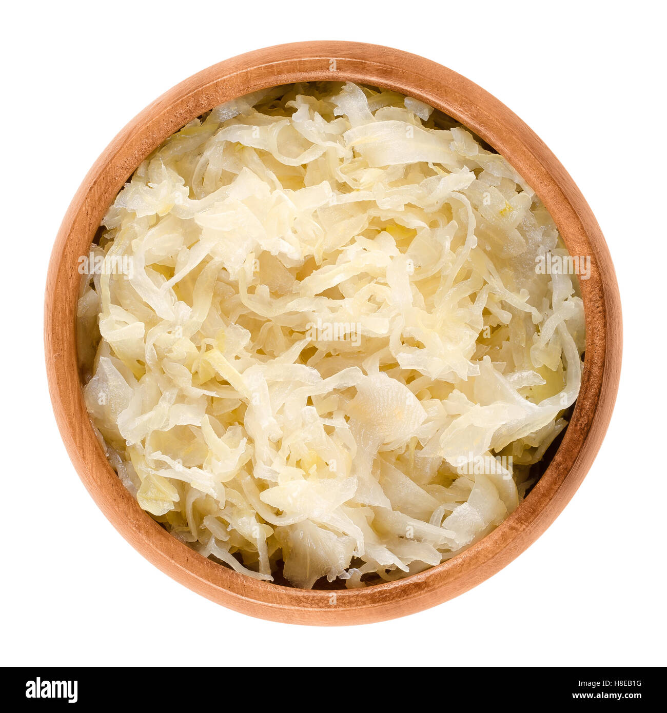 German sauerkraut in wooden bowl over white. Finely cut cabbage, fermented by lactic acid bacteria with long shelf life. Stock Photo