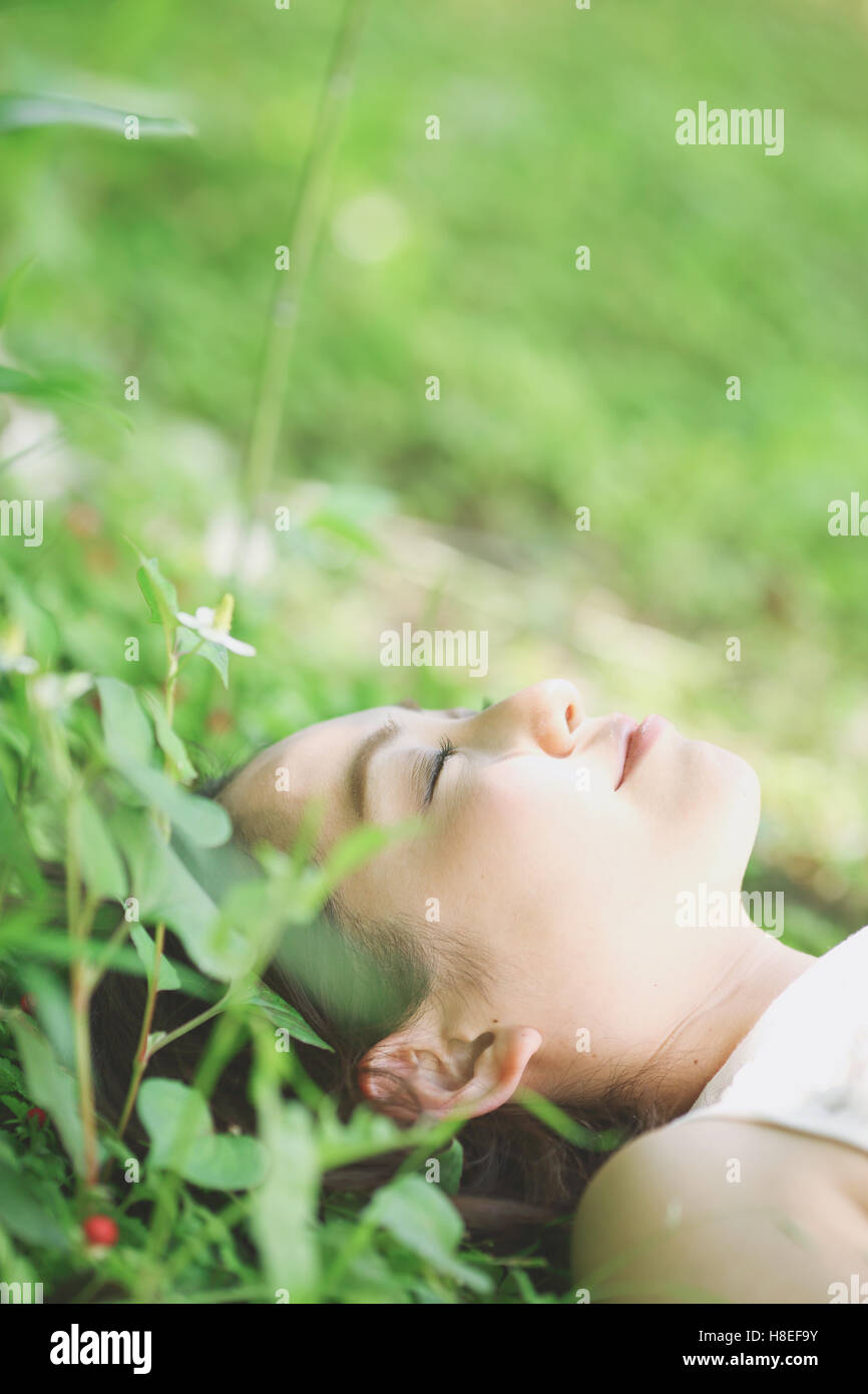 Portrait of young Japanese woman laying on green grass Stock Photo