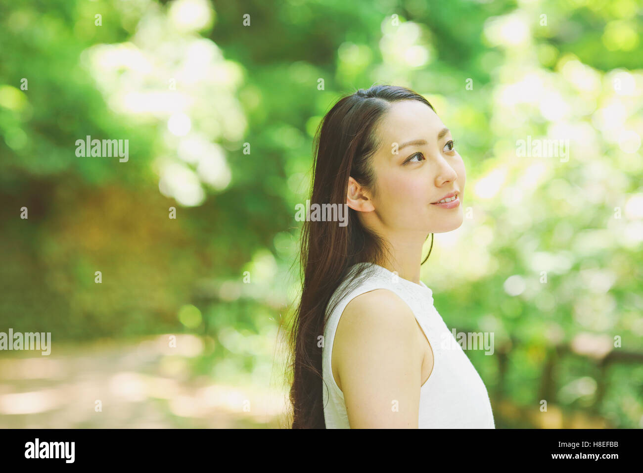 Young Japanese woman surrounded by green in a city park Stock Photo