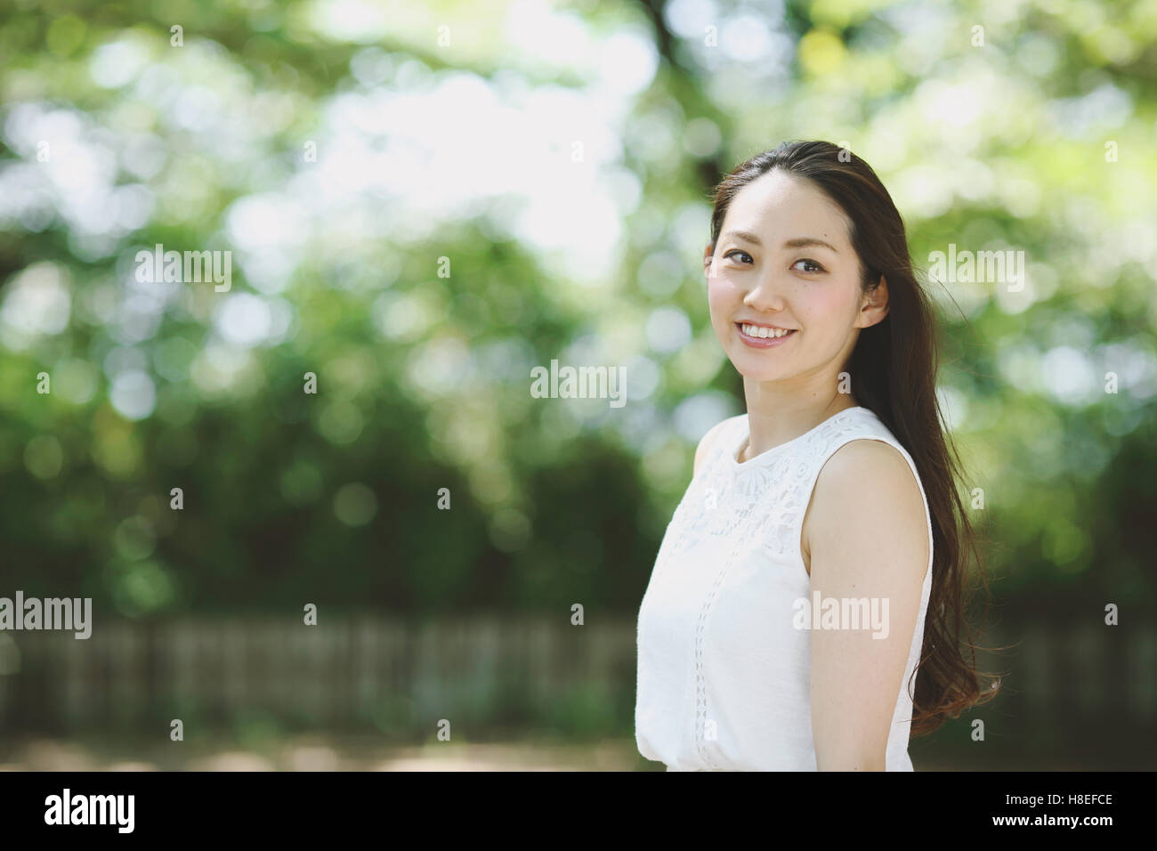 Young Japanese woman surrounded by green in a city park Stock Photo