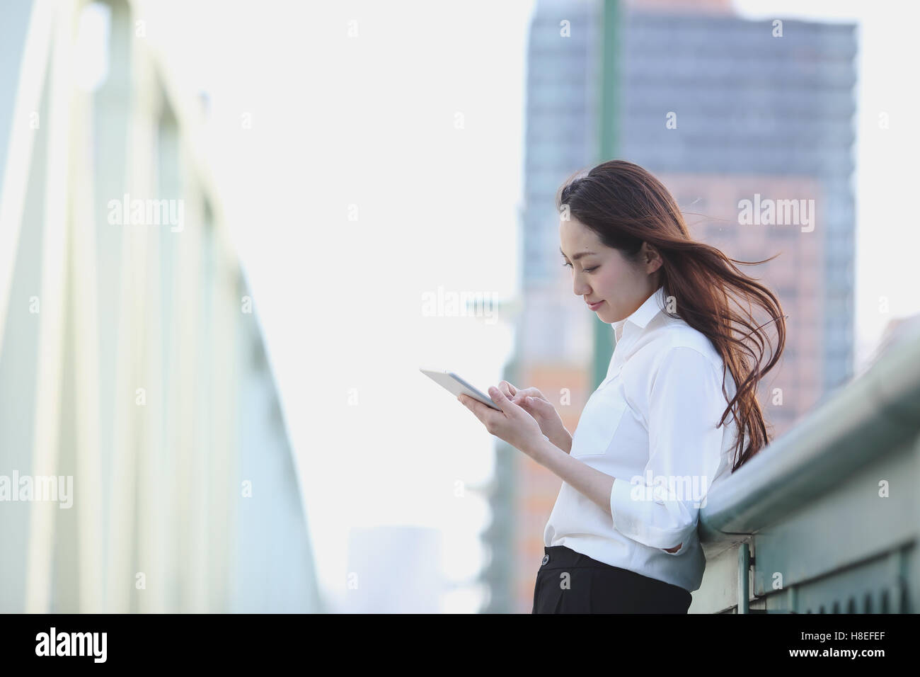 Young Japanese businesswoman with tablet by a river downtown Tokyo Stock Photo
