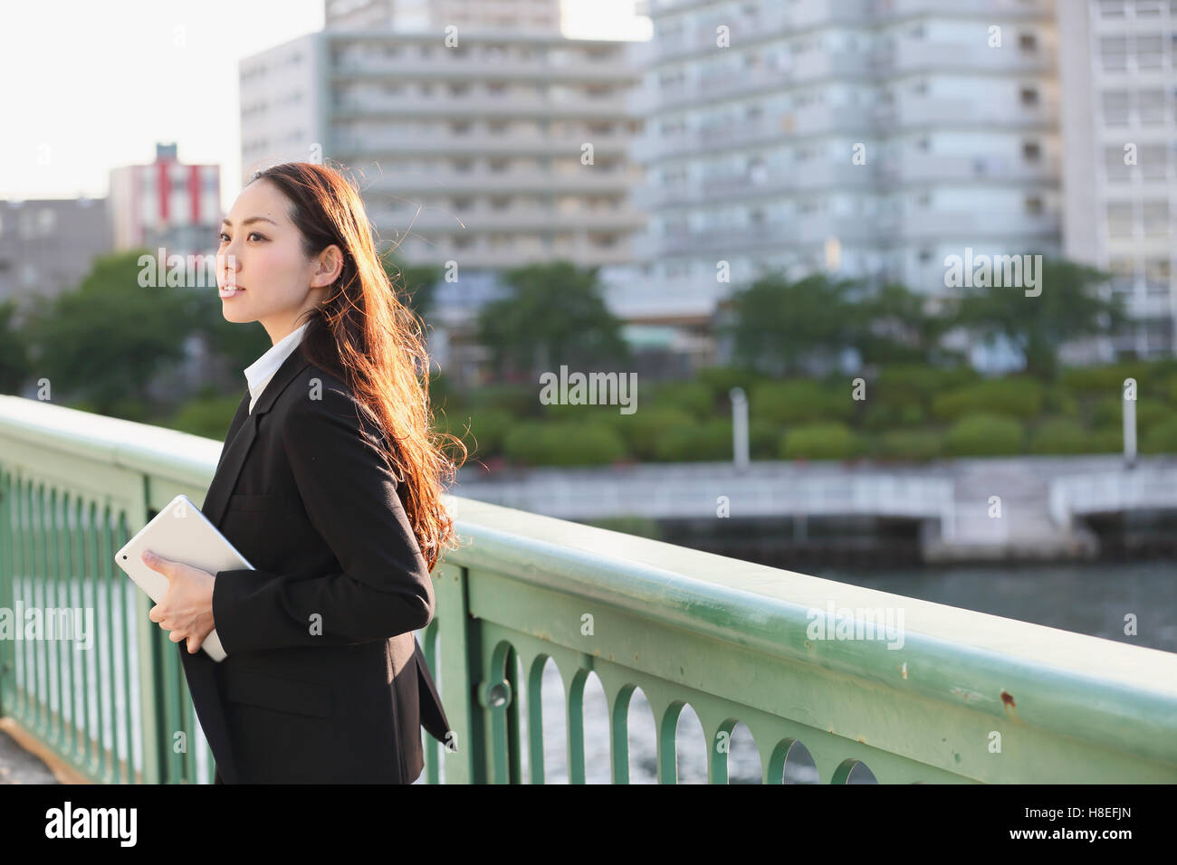 Portrait of young Japanese businesswoman by a river downtown Tokyo Stock Photo