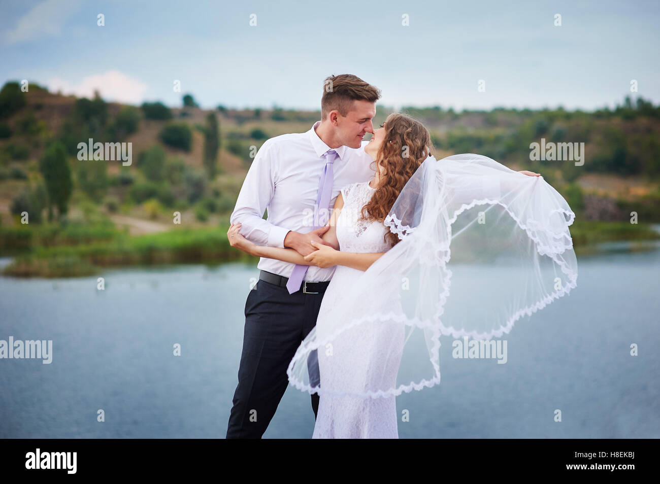 bride and groom hugging at the background of water Stock Photo