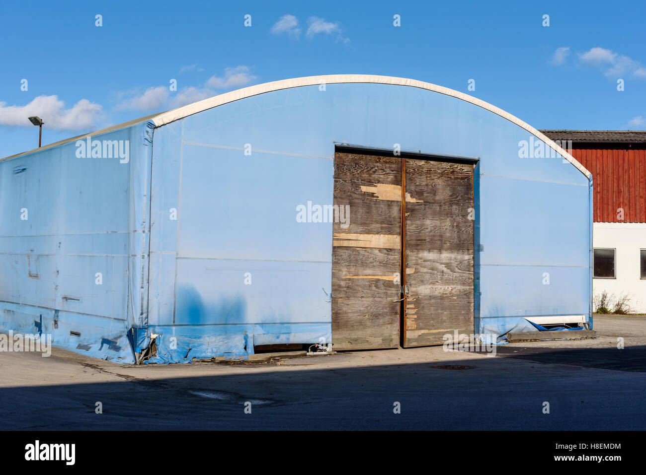 Temporary blue storehouse in industrial area. The outer cover and door is weathered and torn. Stock Photo