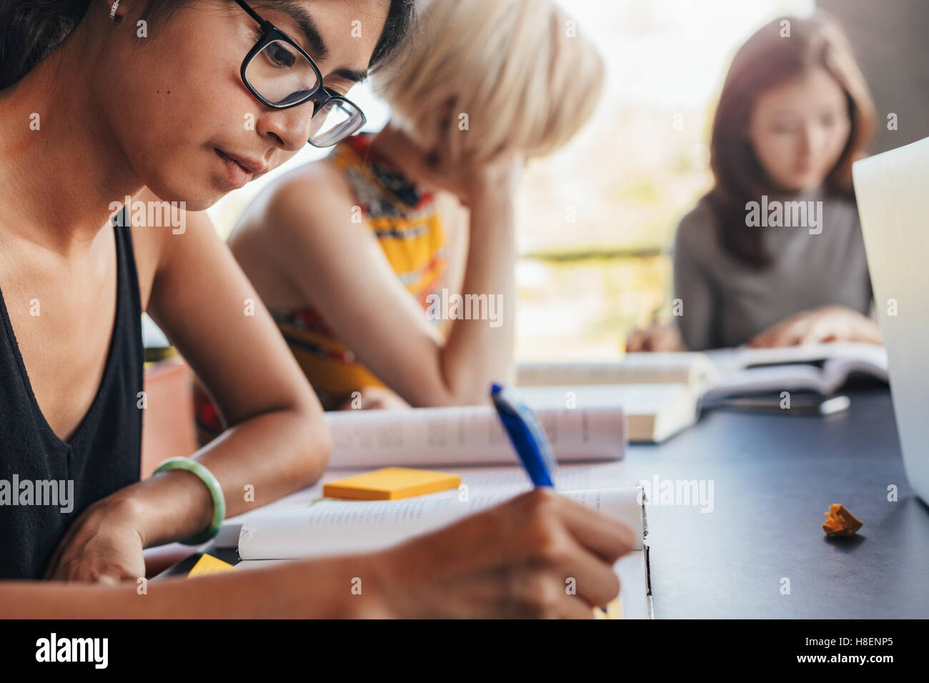 Young asian woman taking notes for her study. Students sitting at table with books and studying. Stock Photo