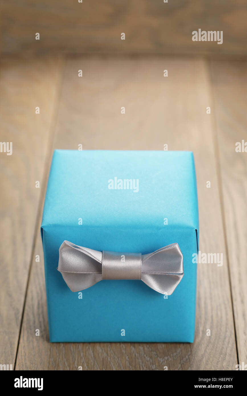 light blue gift box with minimalistic silver ribbon bow on wooden table Stock Photo