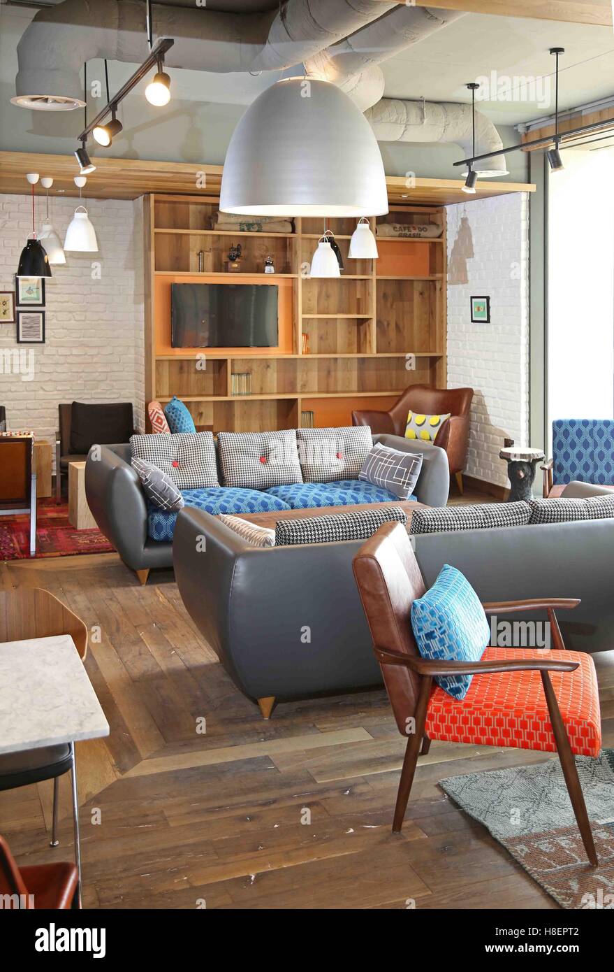 Lounge and reception area in a new Ibis Hotel in Cambridge, UK. Shows vintage style sofas, armchairs tables and shelves Stock Photo