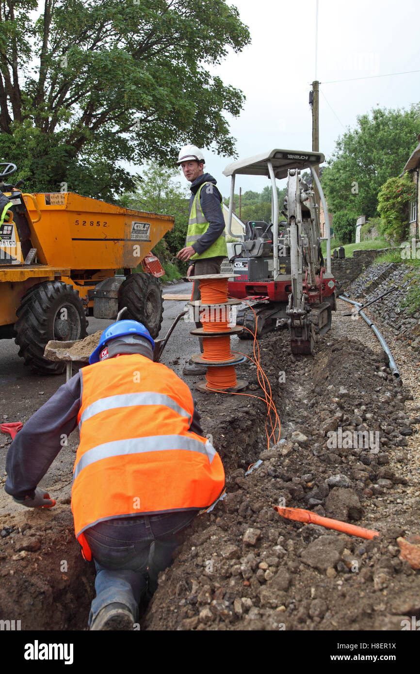 Workmen installing cables for superfast broadband in a rural Oxfordshire village, UK. Shows drums of orange optical cable. Stock Photo