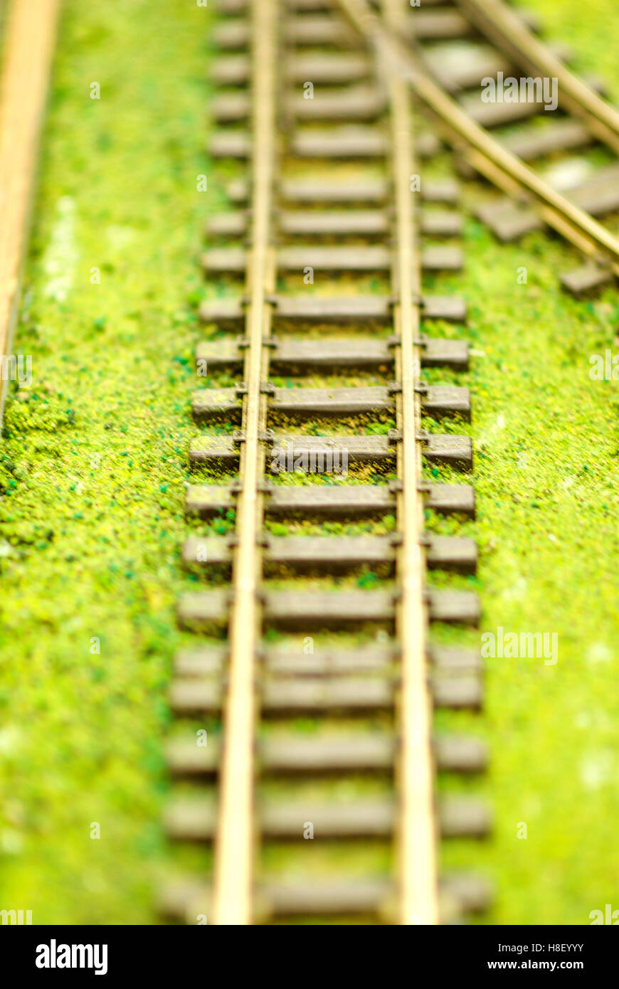 Close-up image of model railroad tracks on fake grass with shallow depth of field. Stock Photo