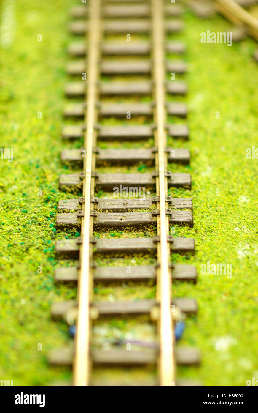 Close-up image of model railroad tracks on fake grass with shallow depth of field. Stock Photo