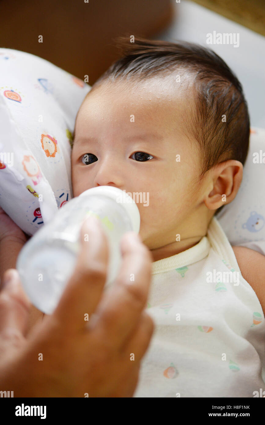 Mother feeding her baby infant from bottle, Baby drinking milk from