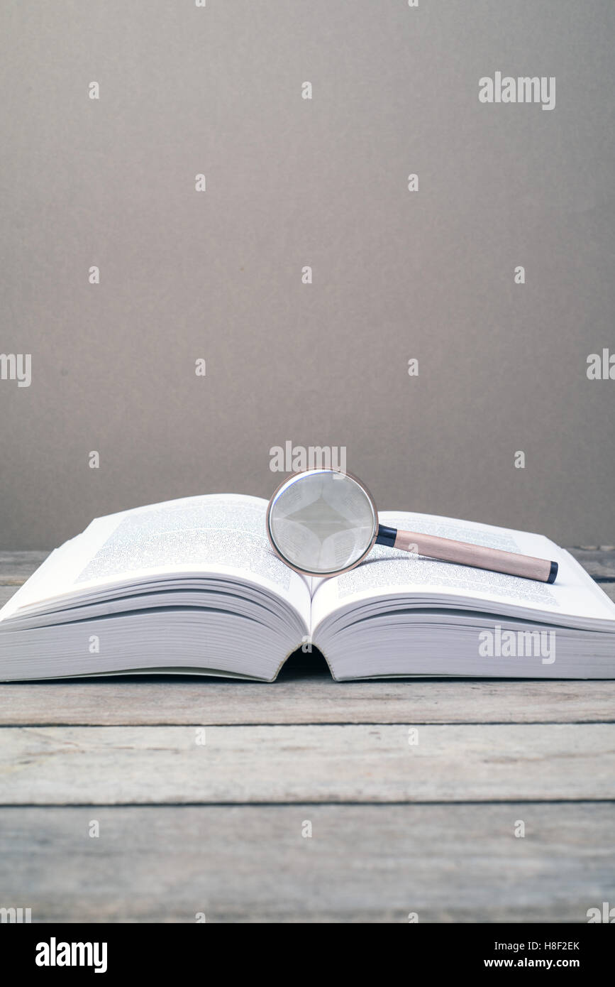 Magnifying glass and blank book on a wooden table. concept of searching for answer, solution or knowledge Stock Photo