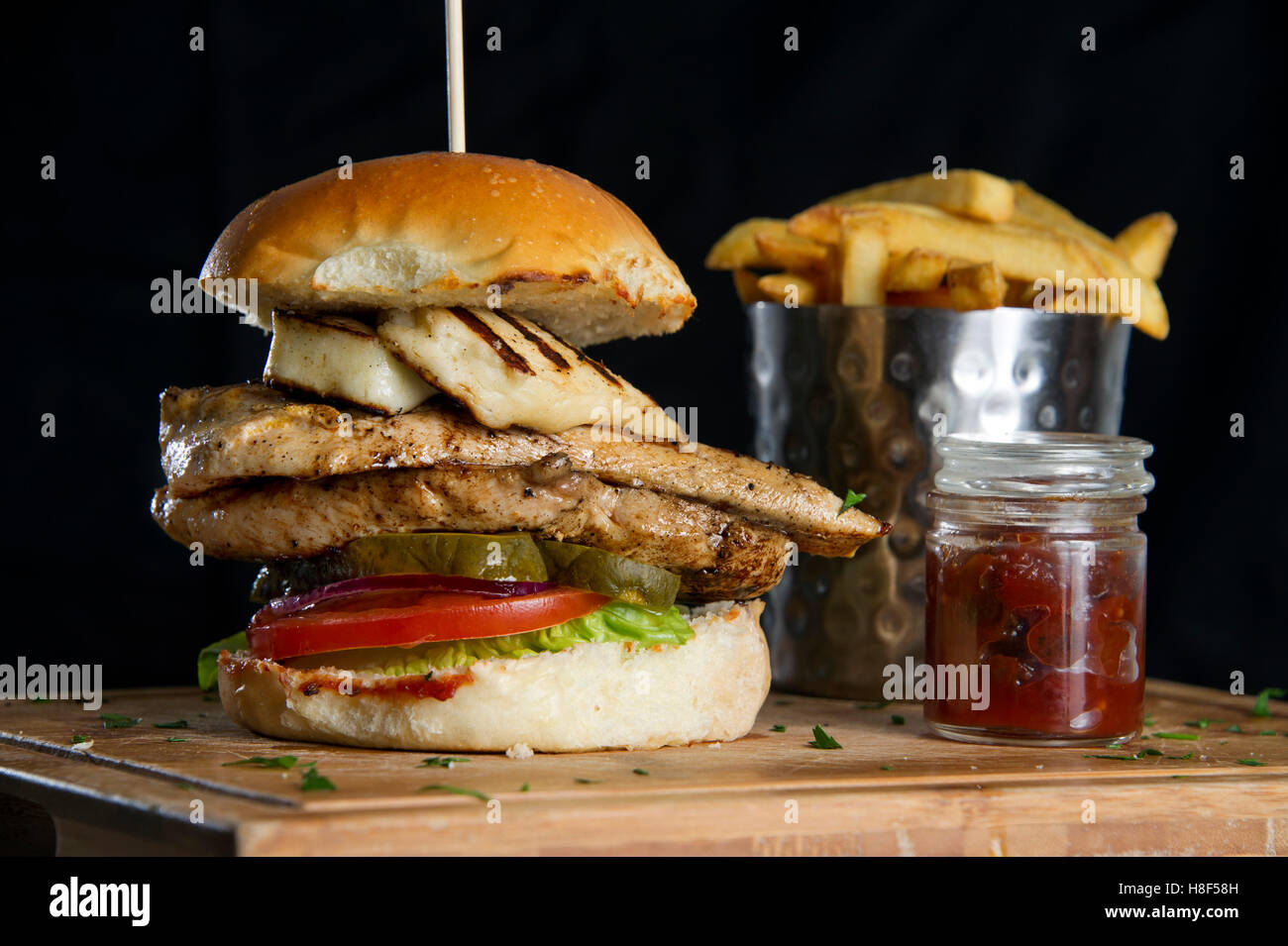 A chicken burger with chips (French fries) on a wooden platter. a UK