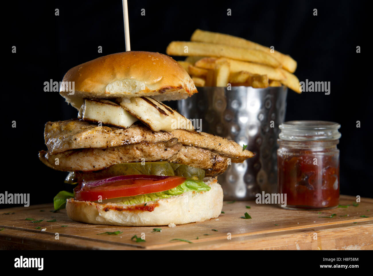 A chicken burger with chips (French fries) on a wooden platter. a UK