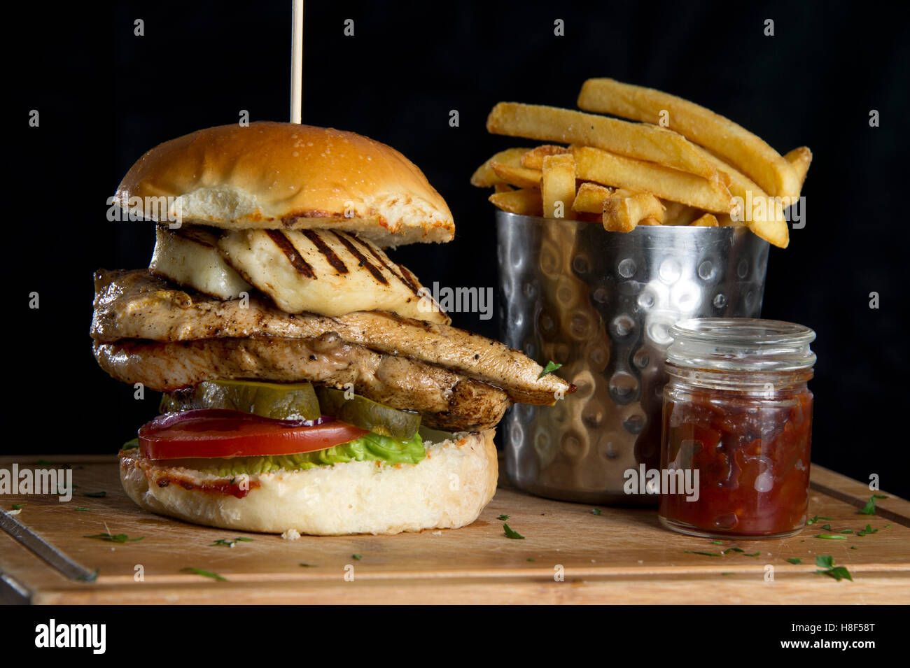 A chicken burger with chips (French fries) on a wooden platter. a UK