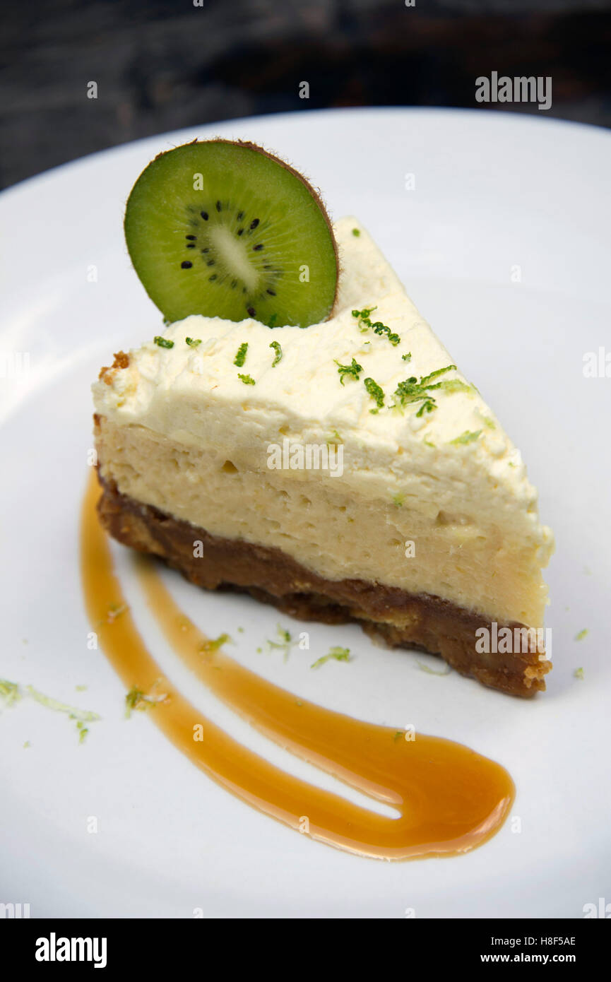 A lemon cheesecake with a slice of kiwifruit garnish. a UK food desert sweet pudding Stock Photo