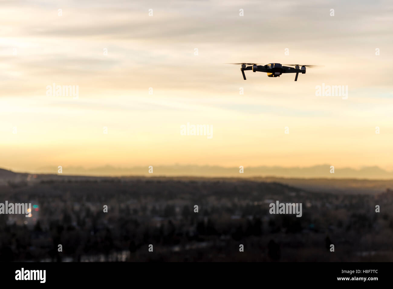 Small modern drone hovering taking picture of sunset Stock Photo