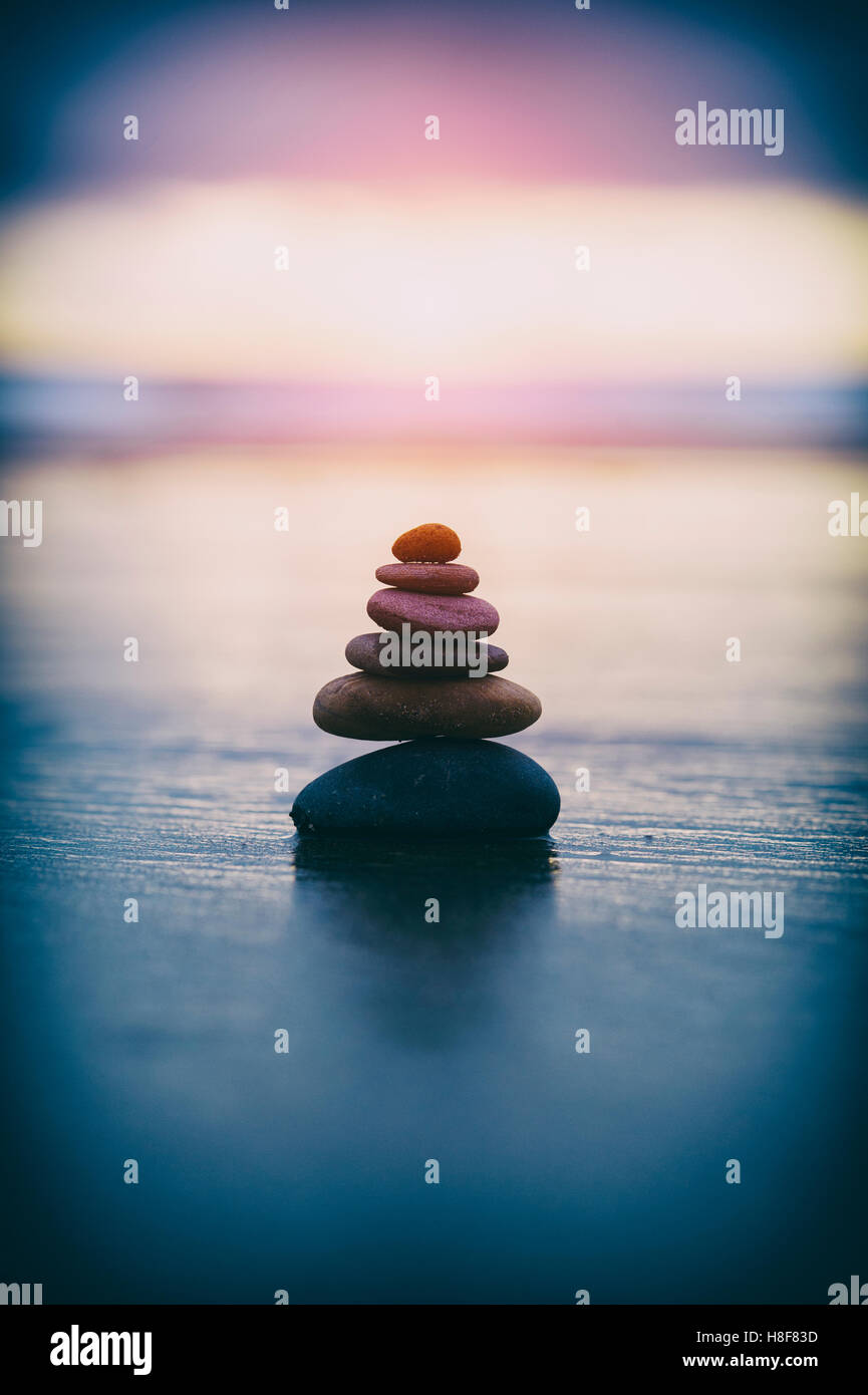 Pebbles balancing on a stormy beach in the early morning light with vintage filter Stock Photo