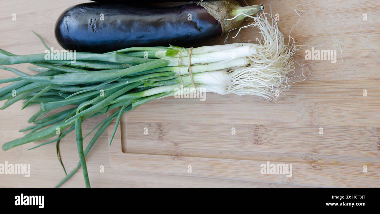 Eggplant with green onions on cutting board Stock Photo