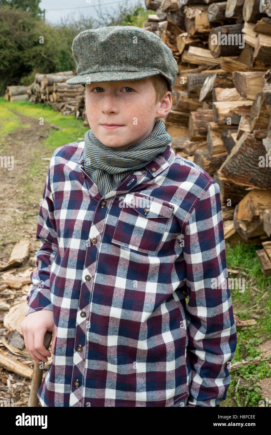 Boy in plaid shirt, scarf, and hat holding an axe in front of a pile of  firewood in a farm Stock Photo - Alamy