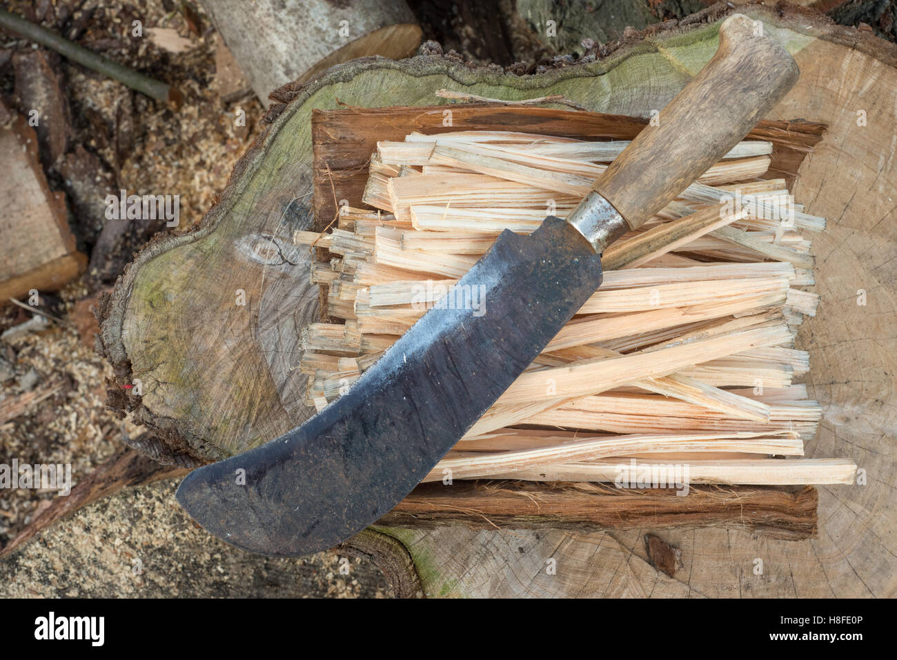 Overhead shot of a machete or billhook knife on a pile of firewood sticks Stock Photo