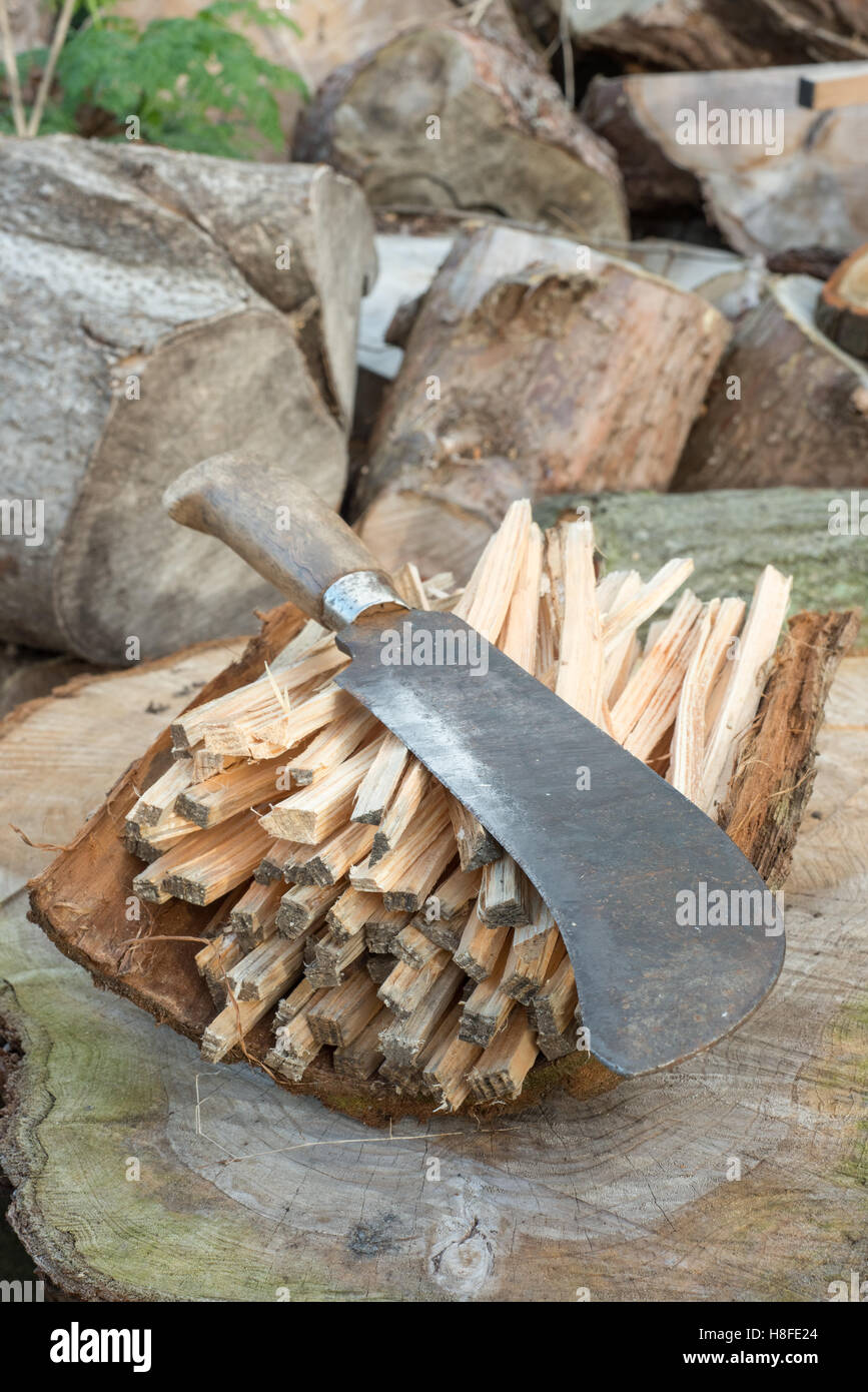 Billhook knife or machete on a pile of firewood sticks Stock Photo