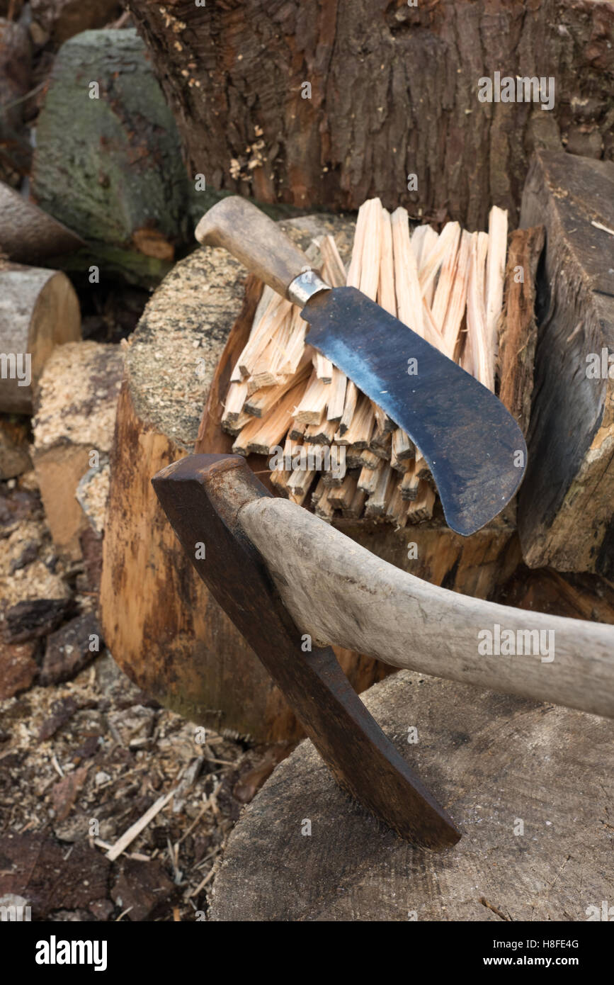 Axe on a log and a machete on a pile of sticks Stock Photo
