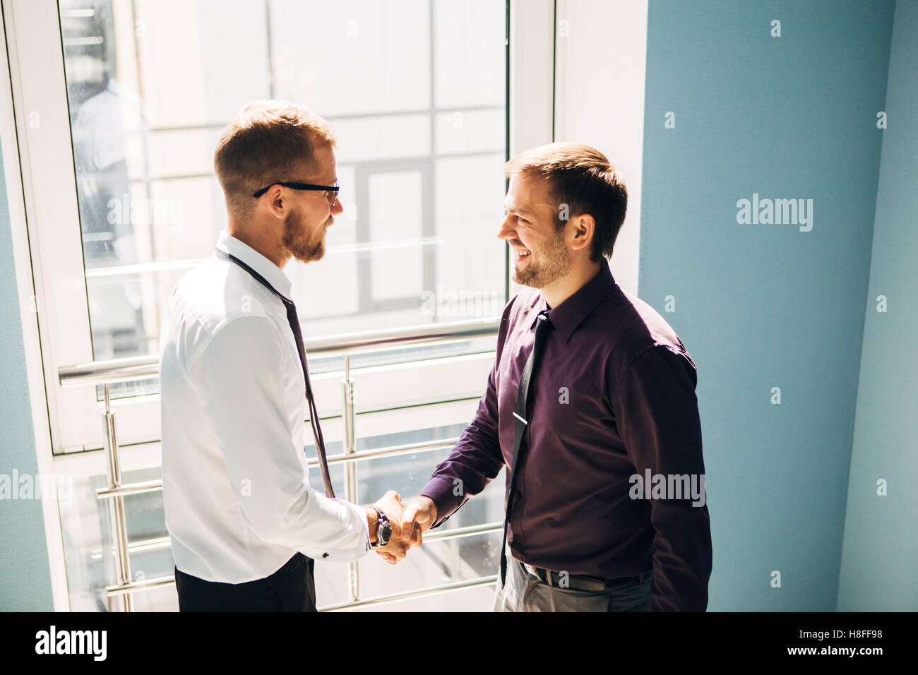 Full length side view of businessmen shaking hands in office building ...
