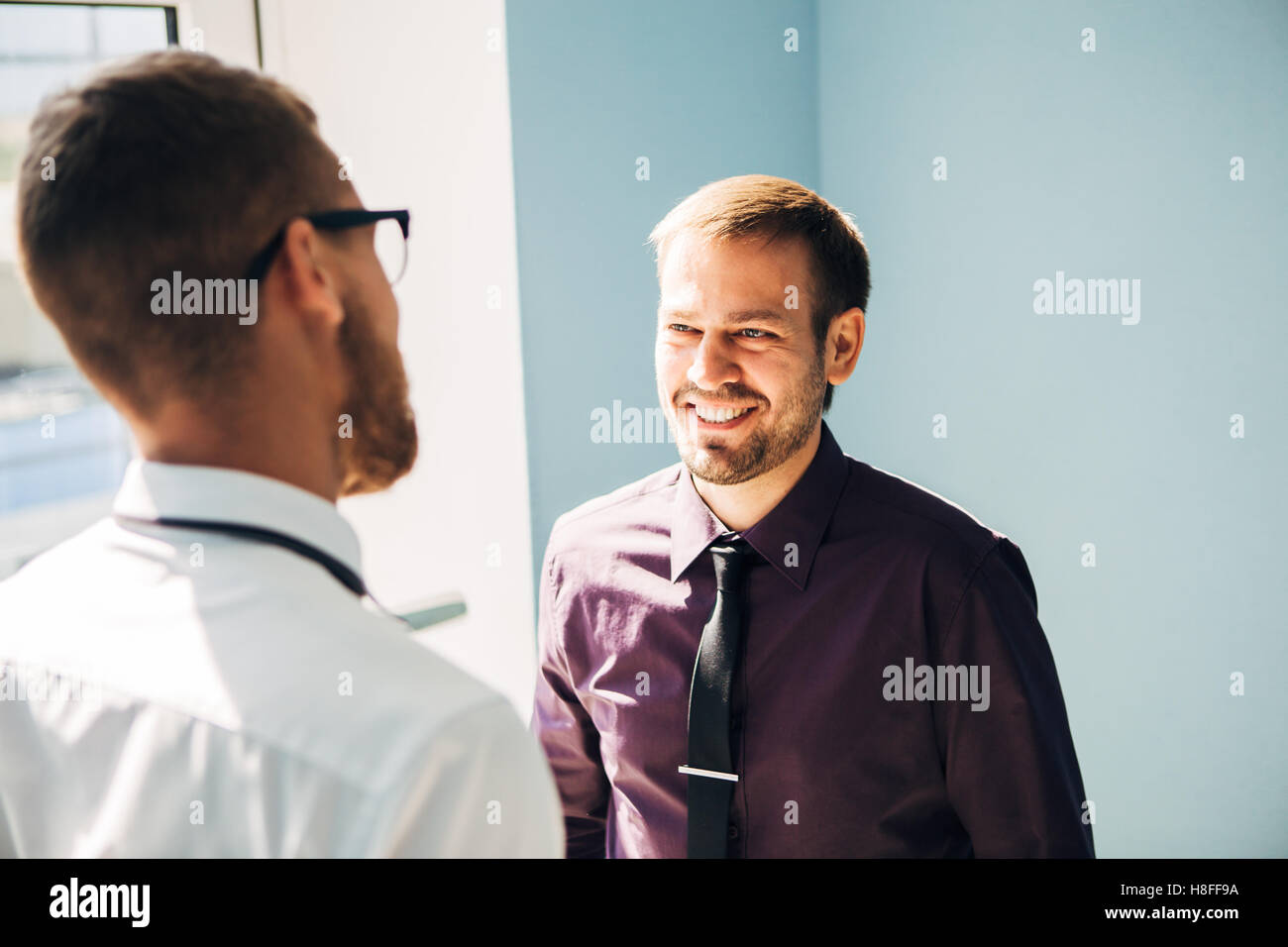 Full length side view of businessmen shaking hands in office building ...