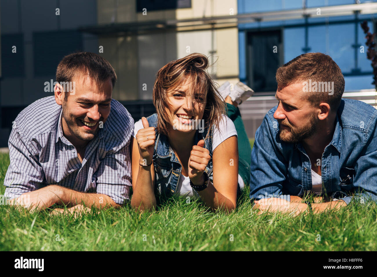three students lying on the grass Stock Photo