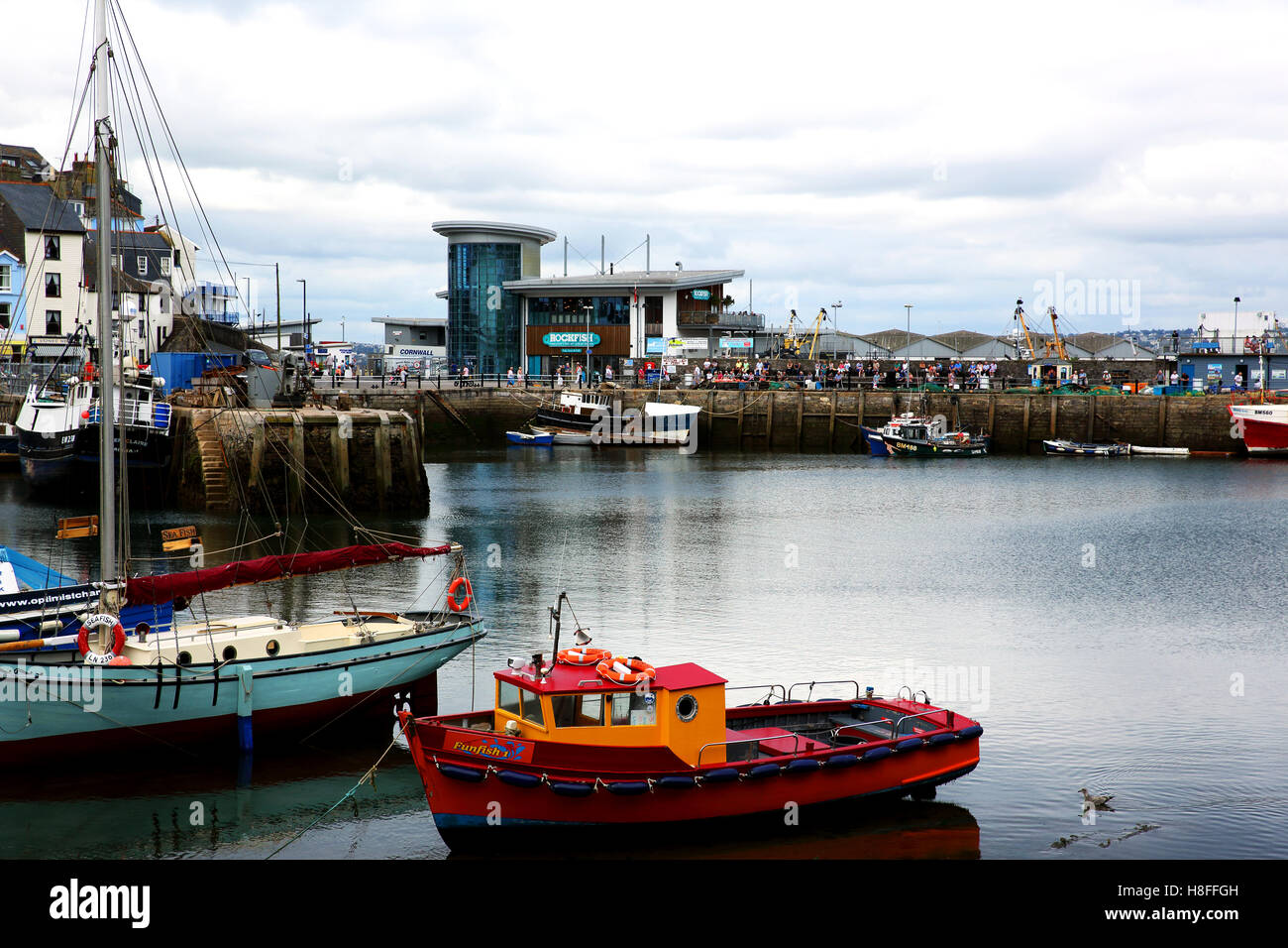 Boats in Brixham harbour, Devon, UK. The Rockfish seafood restaurant and many tourists can be seen in the background. Stock Photo