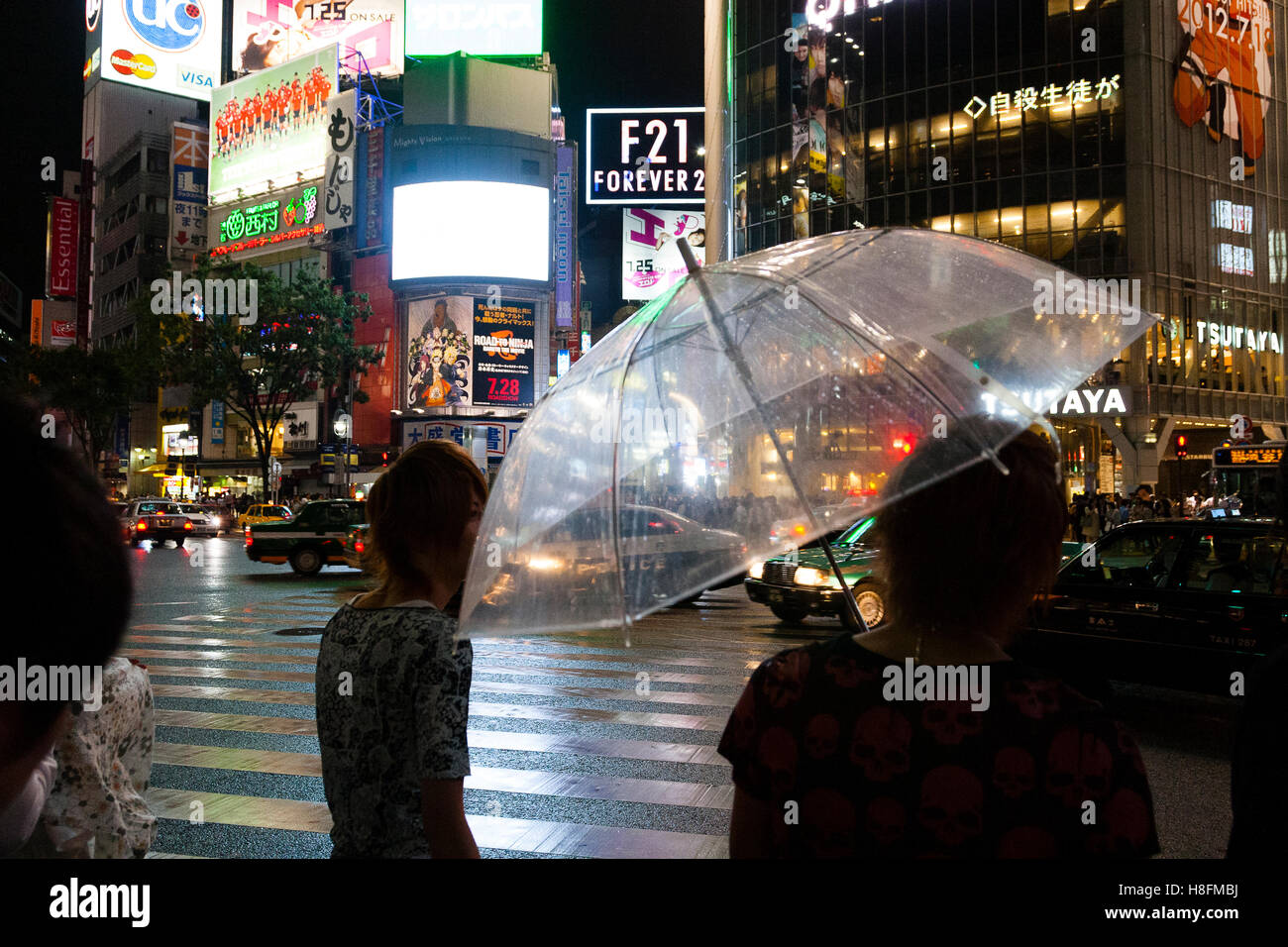 TOKYO, JAPAN Pedestrians holding an umbrella  wait to cross the street in Tokyo's Shibuya district. Stock Photo