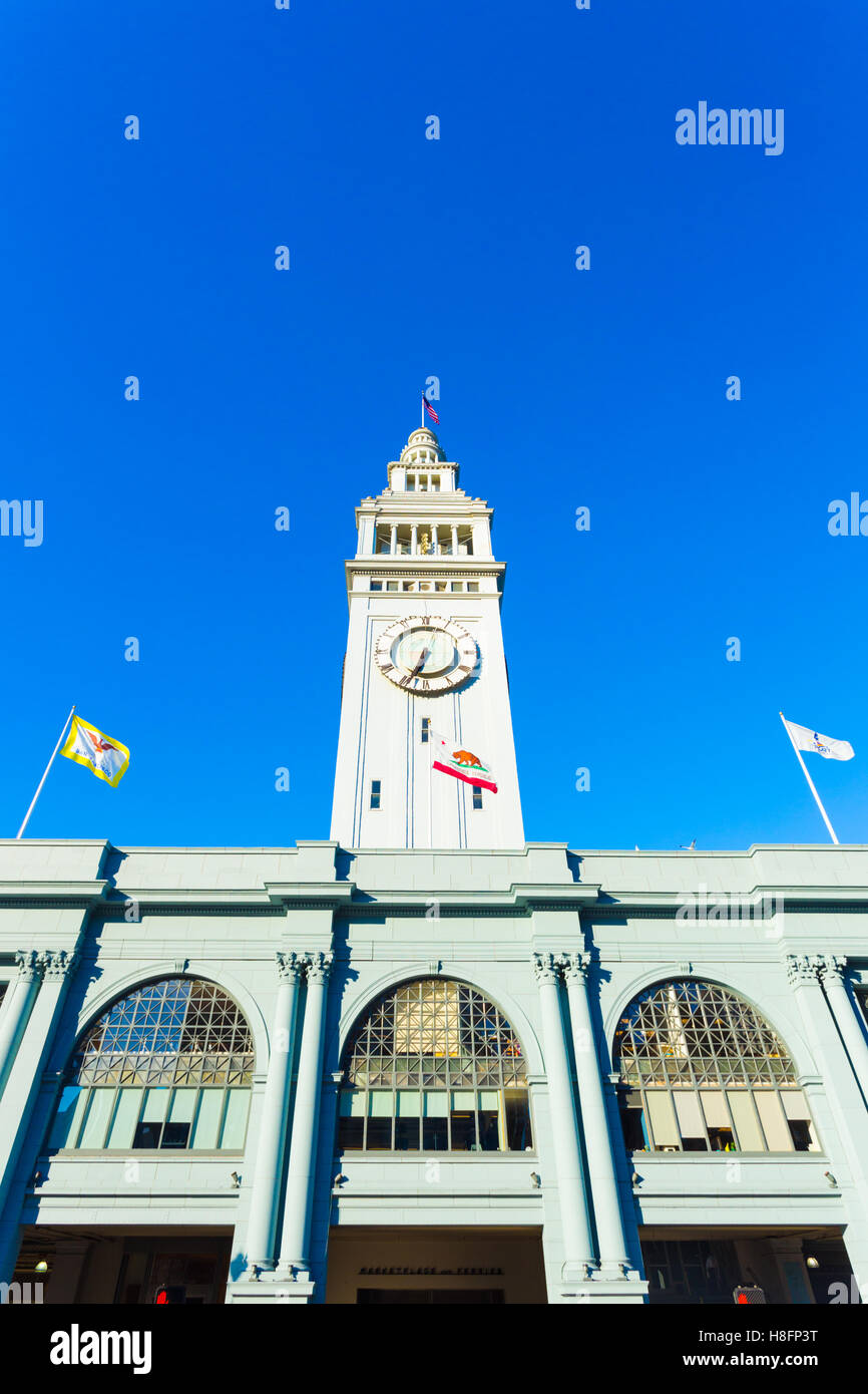 Daytime front facade of centered Ferry Building and clock tower looking up from a low angle on blue sky day in San Francisco Stock Photo