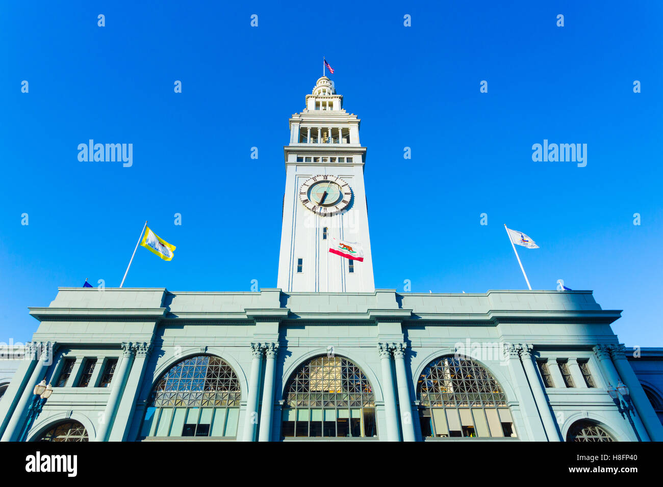 Day front facade view of centered Ferry Building and clock tower looking up from a low angle on a sunny day in San Francisco Stock Photo