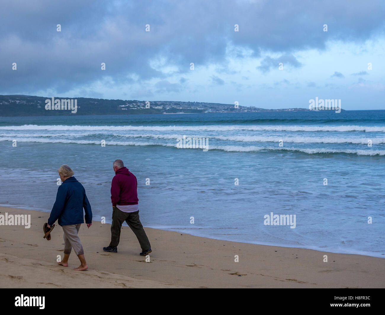 Elderly couple walking down the beach in Cornwall. Stock Photo