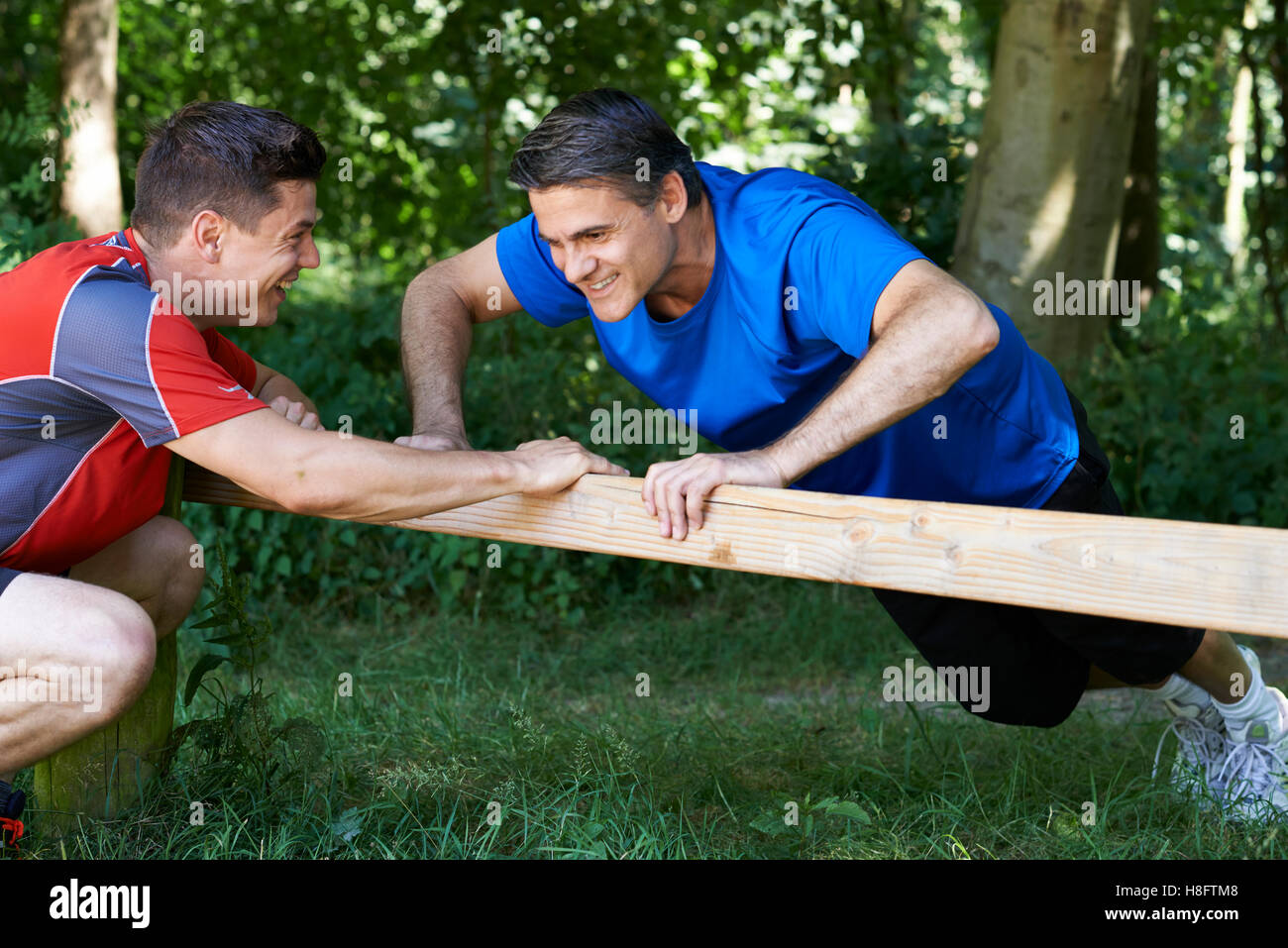 Mature Man Exercising With Personal Trainer In Park Stock Photo