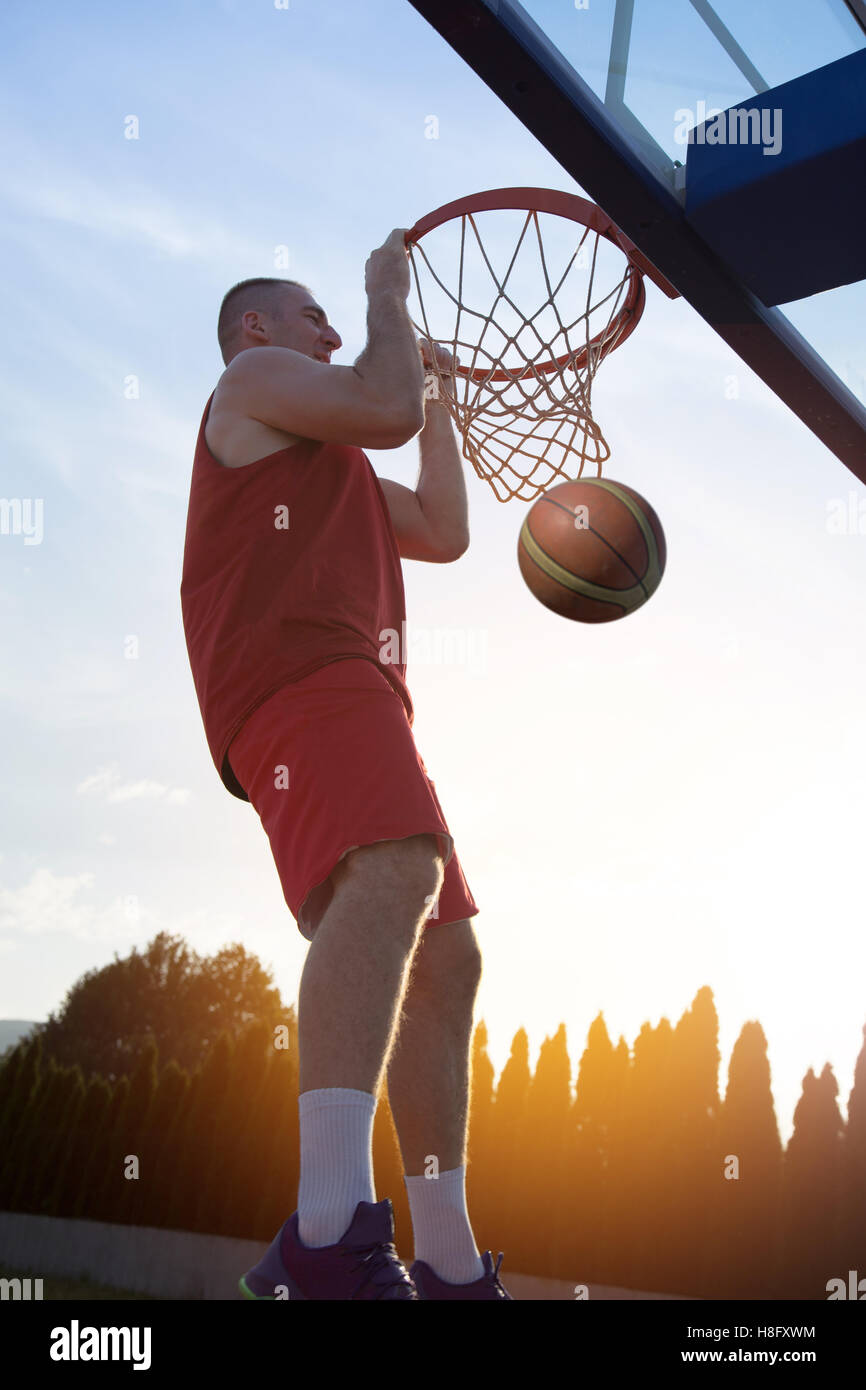 Young man jumping and making a fantastic slam dunk playing stree Stock Photo