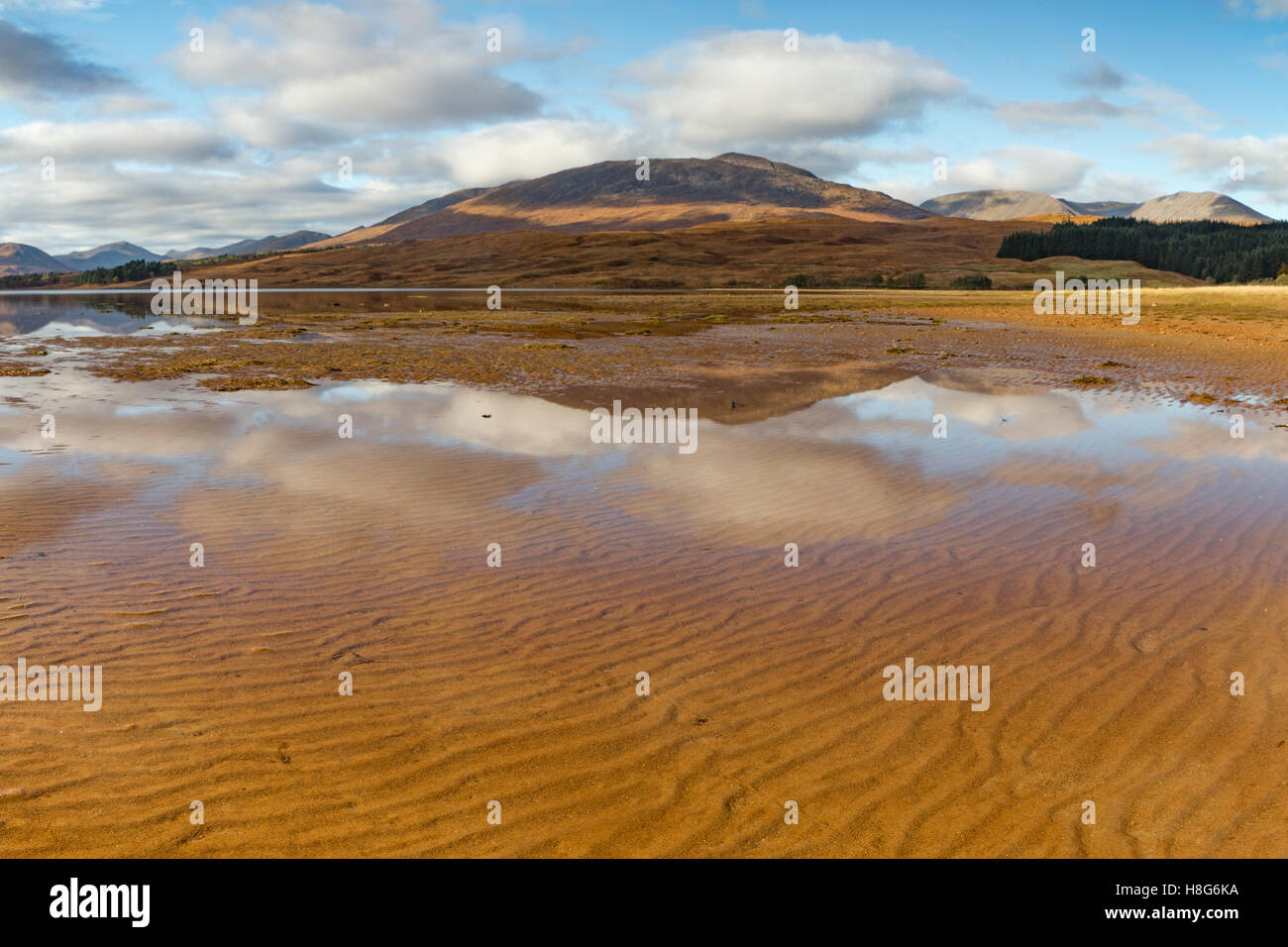 The sand ripples appear through the shallow water in Loch Tulla, Glen coe, Scotland. Stock Photo