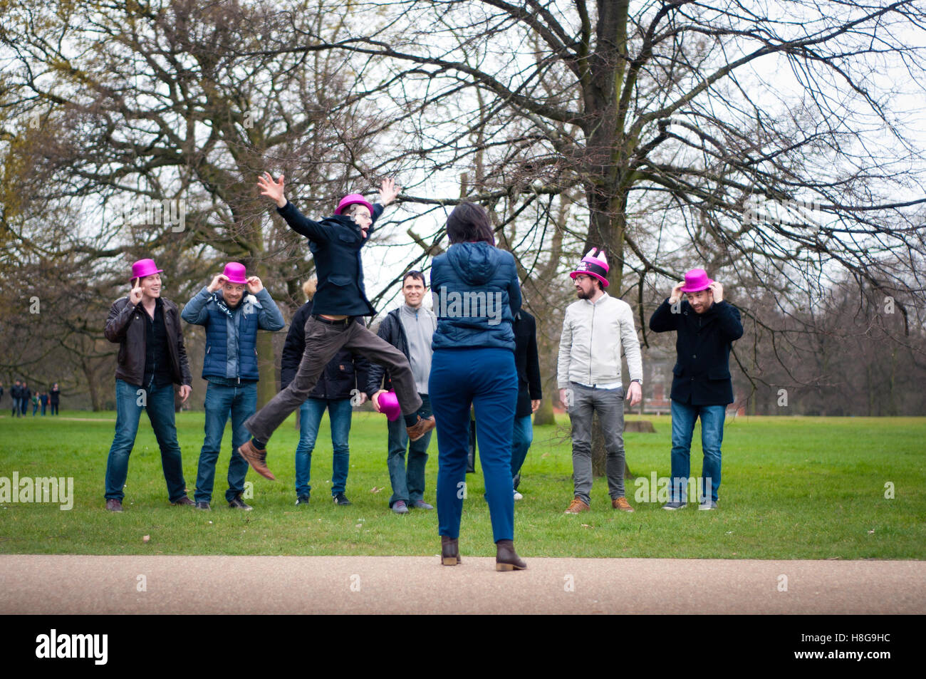 London: Group of men looking at a lady's camera and involving her at Hyde Park. They came from France for a Stag Night. Stock Photo