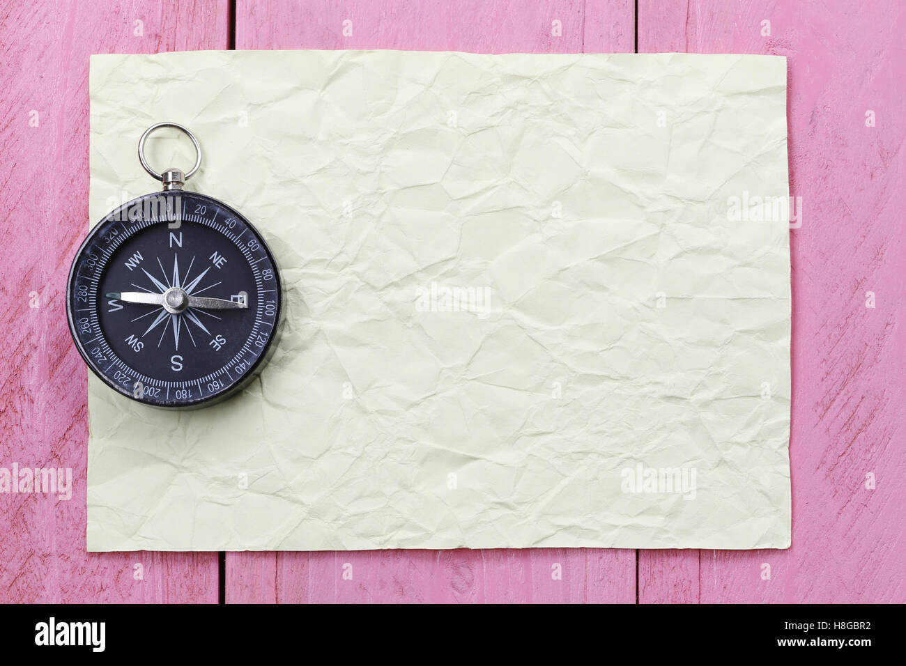 Compass and note paper on the pink wooden floor,concept of traveling and trekking. Stock Photo