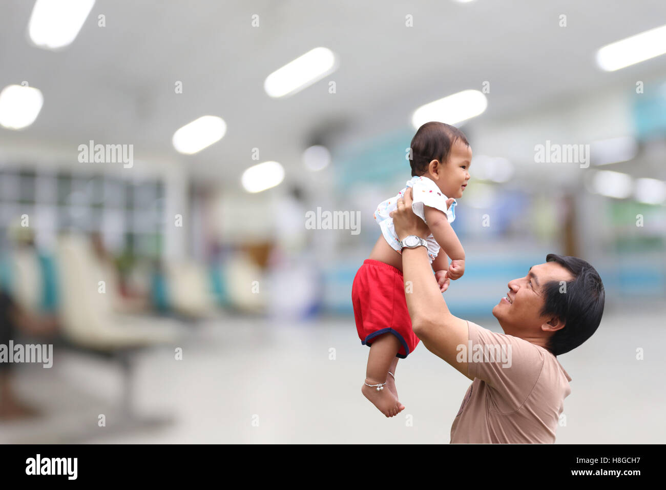 Man were holding a baby to holds up and blurred hospital background,concept of love in the family. Stock Photo