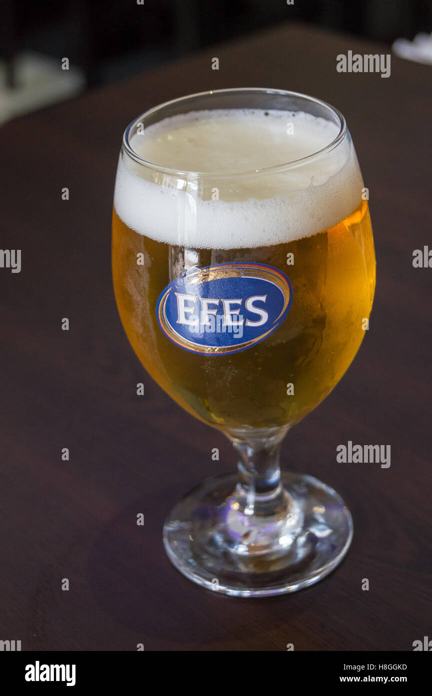 A printed glass of Efes Turkish beer on a table in a restaurant bar  in London, England, pub table drinks glasses Stock Photo