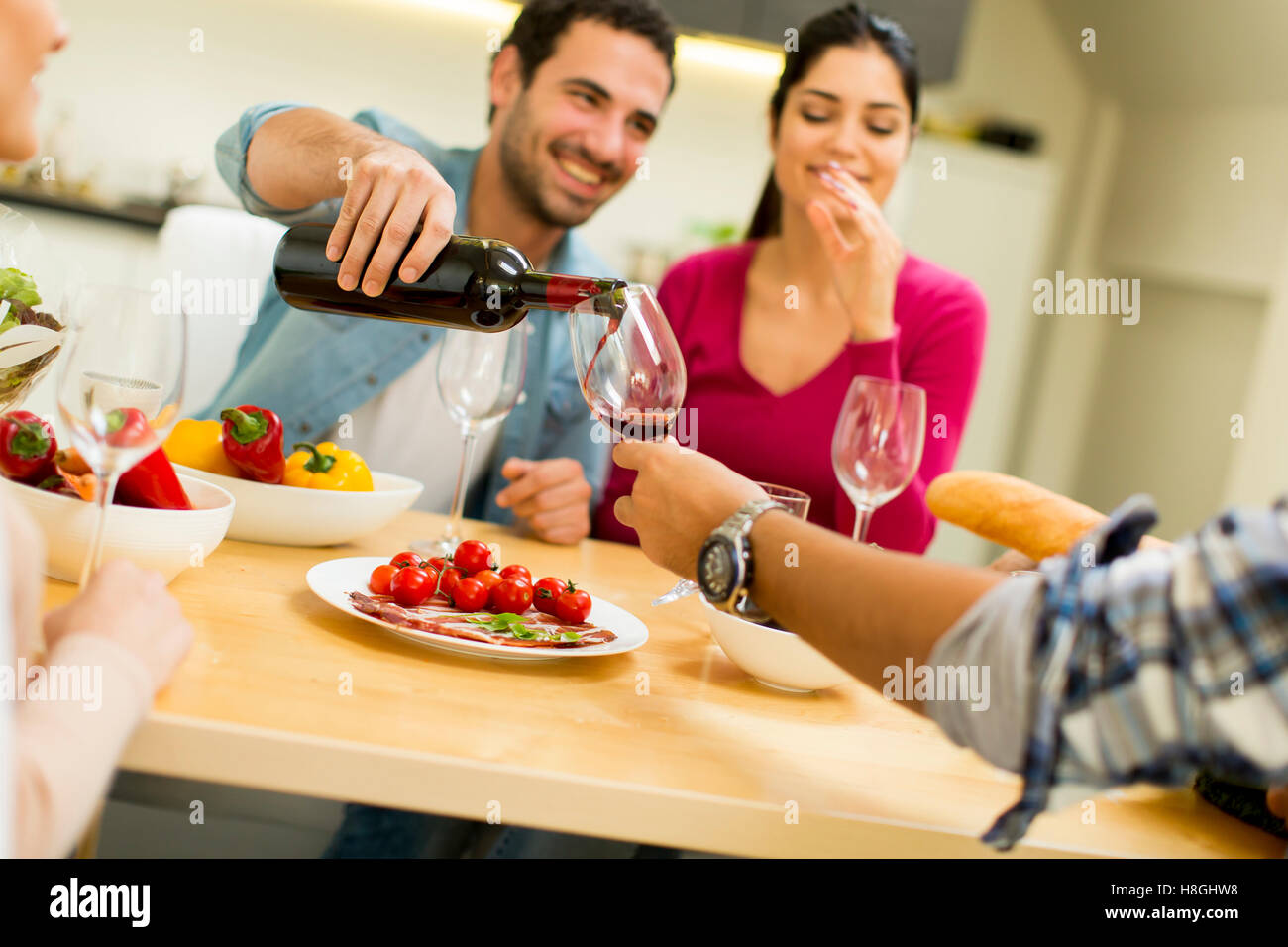 Group of happ young people sitting by the table eating and drinking red wine Stock Photo Alamy
