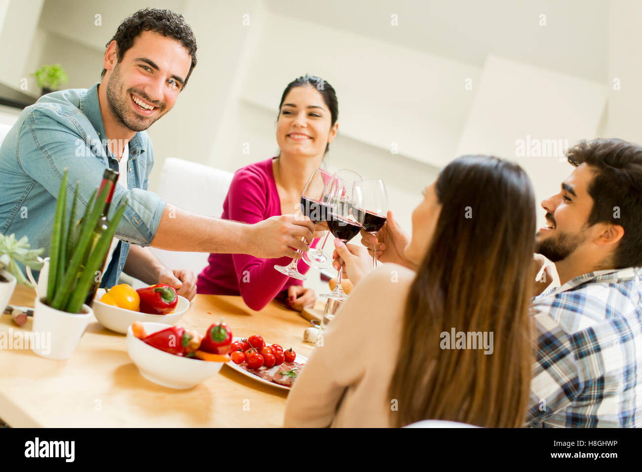 Group of happ young people sitting by the table eating and drinking red wine Stock Photo Alamy