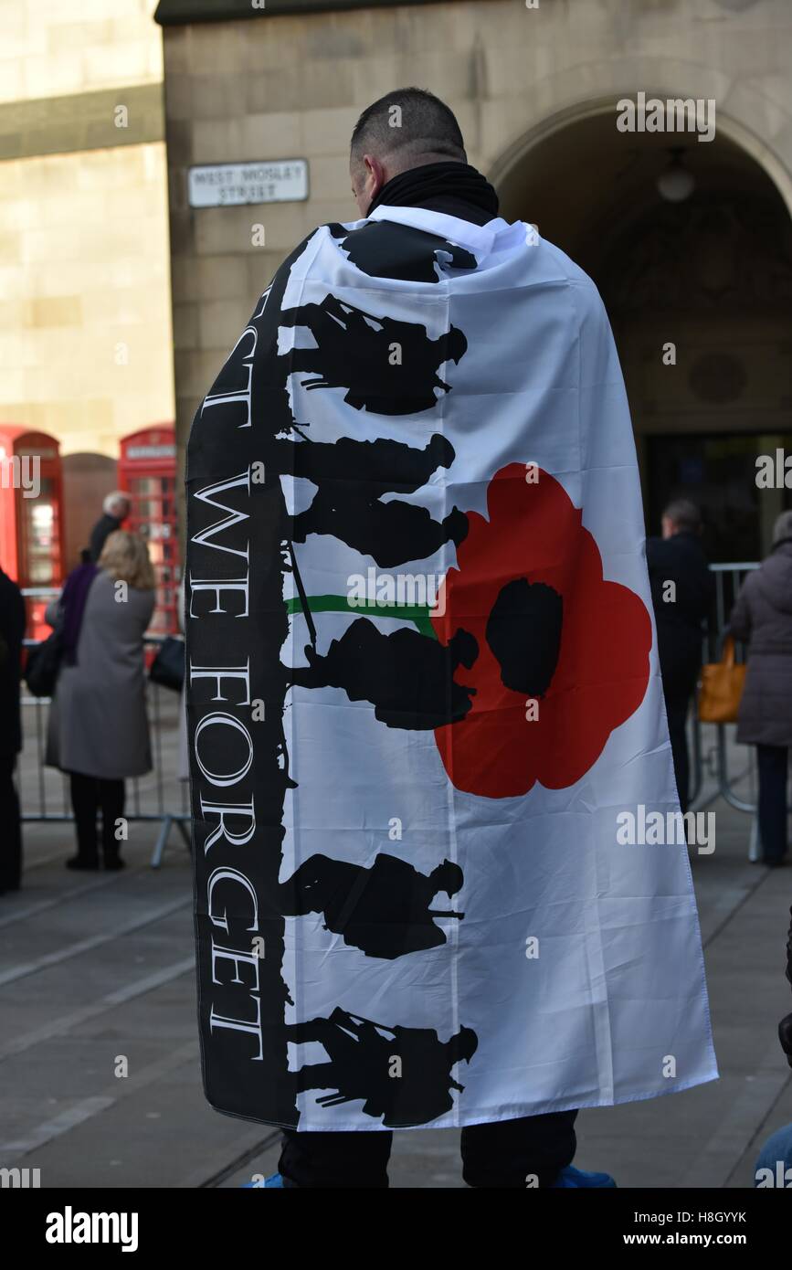 Manchester  UK  13th November 2016  A man with a flag stating 'Least We Forget' watches the proceedings at the Remembrance Day service at the cenotaph in central Manchester Credit:  John Fryer/Alamy Live News Stock Photo