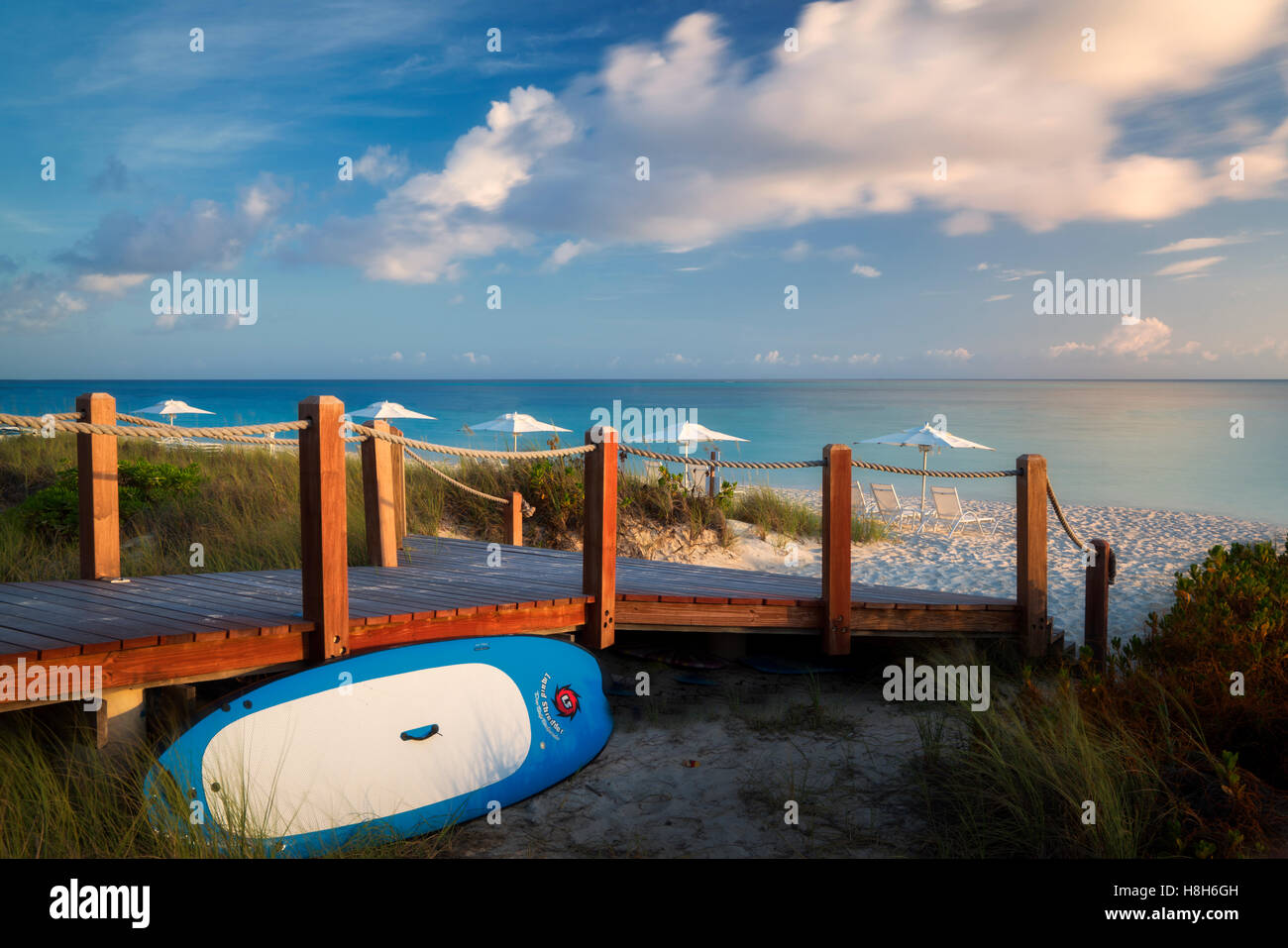 Pathway to ocean with surf board and beach umbrellas. Turks and Caicos. Providenciales. Stock Photo