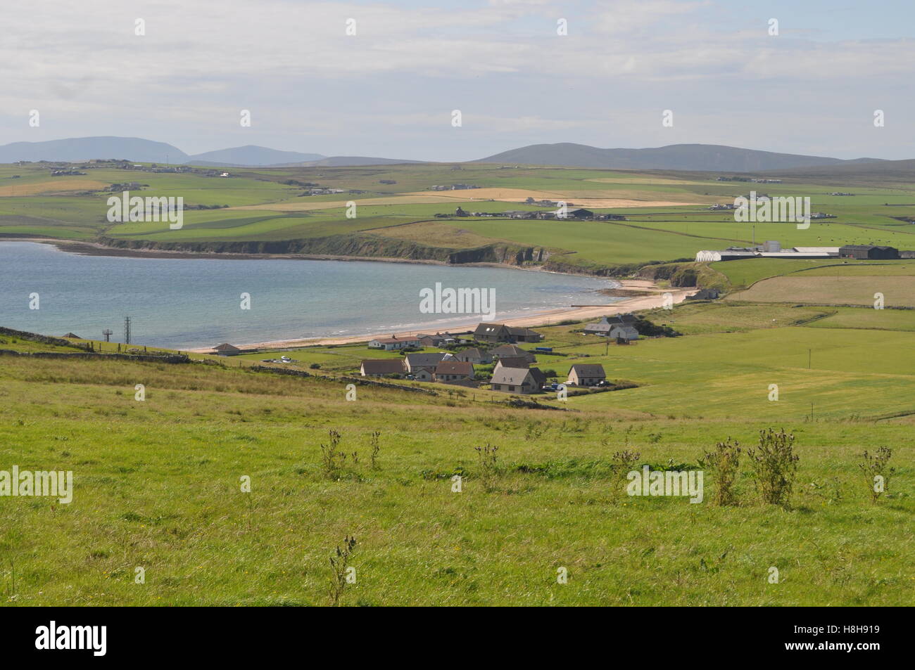Small village of grey stone cottages and houses next to the beach at Scapa Bay, Orkney, Scotland Stock Photo