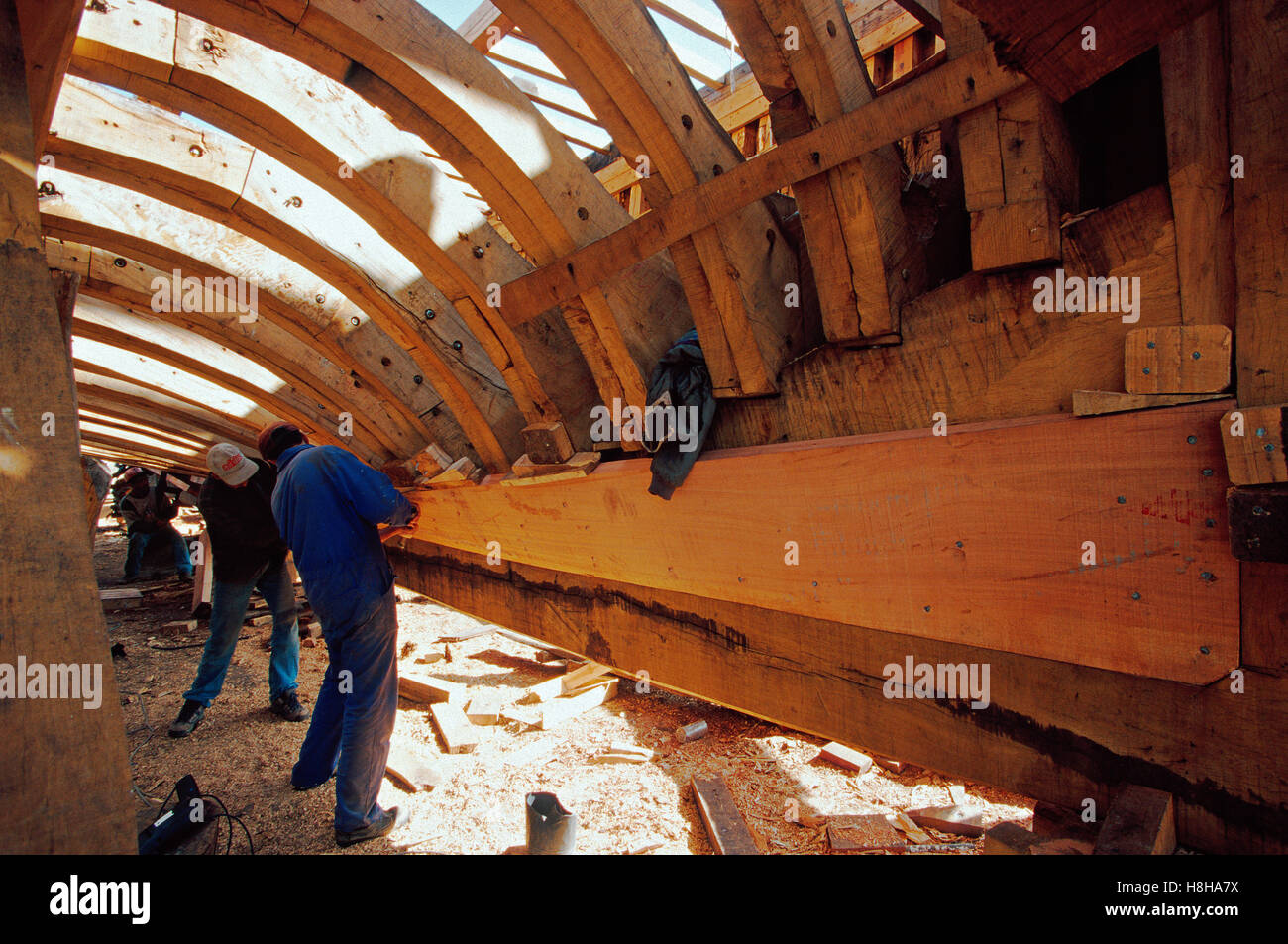 Shipwright under the hull of a trawler in the shipyard of Essaouira, Morocco, North Africa Stock Photo